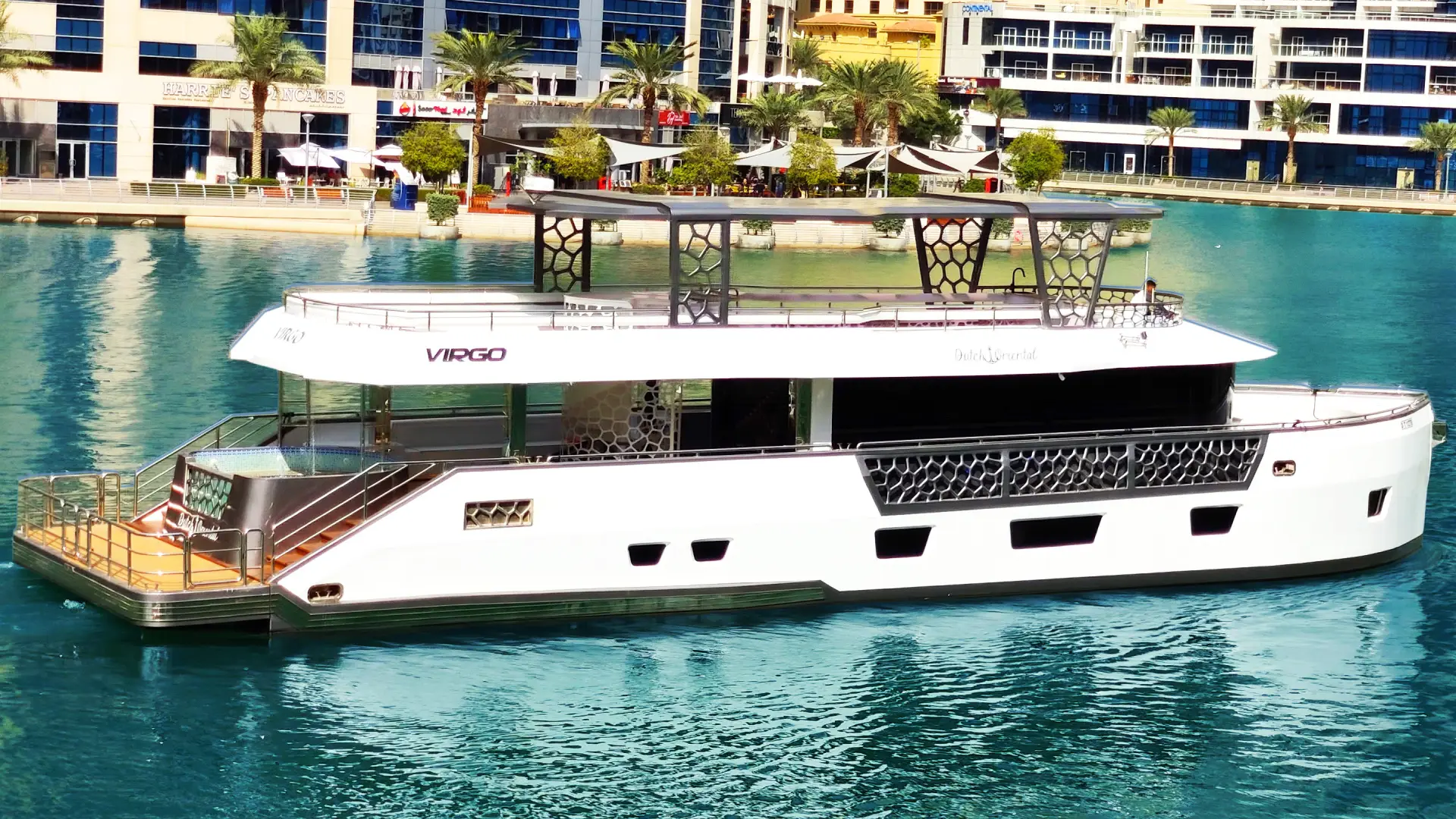 Evening view of Virgo Yacht lit with warm lights under Dubai skyline – nighttime luxury with Mala Yachts yacht rental Dubai