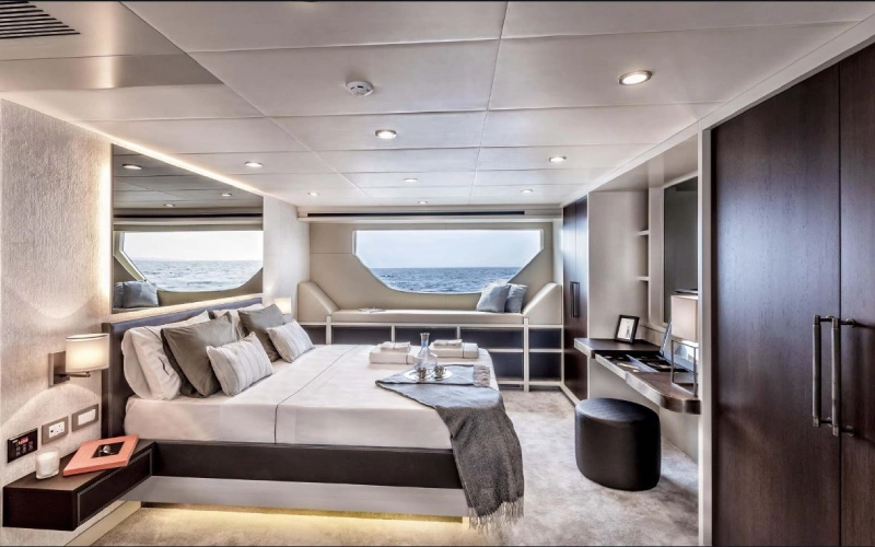 "Luxurious bedroom on Dolce Vita Yacht with a queen-size bed, soft ambient lighting, and a large ocean-view window"
