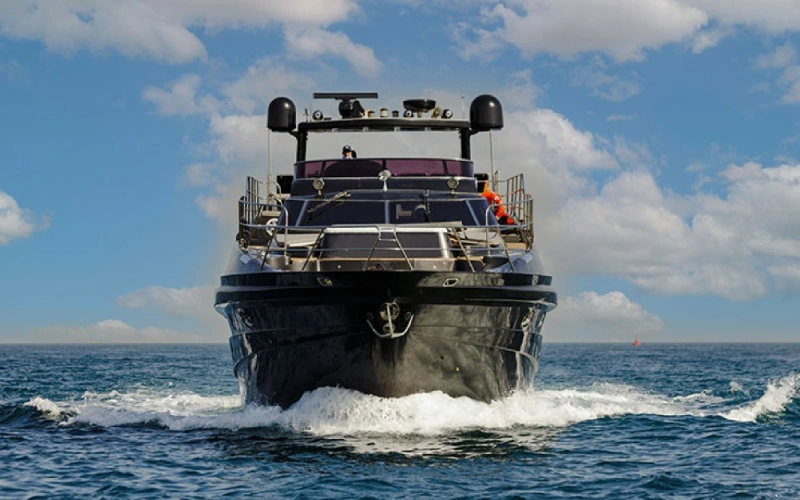 Side view of Black Beauty Yacht cruising on deep blue waters with a bold black finish
