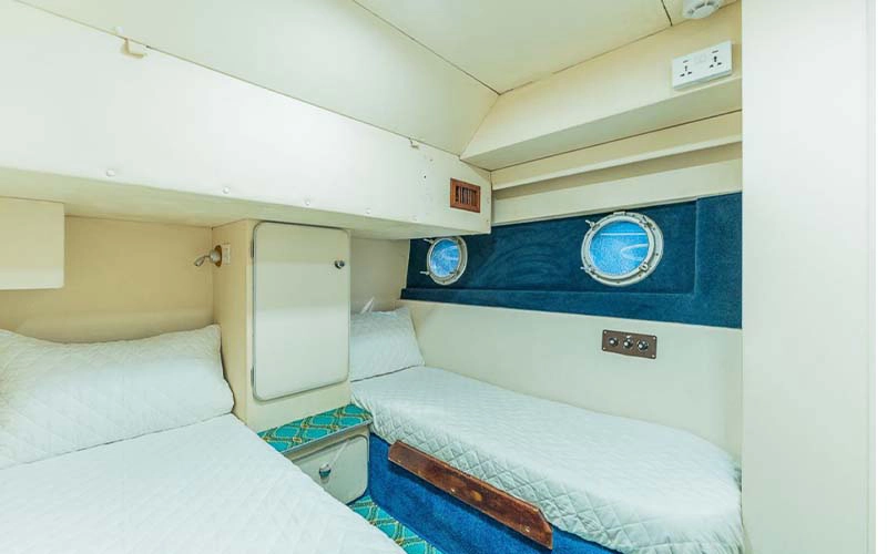 Twin bedroom on Sasmi 48ft Yacht featuring two single beds, wooden cabinets, and soft ambient lighting
