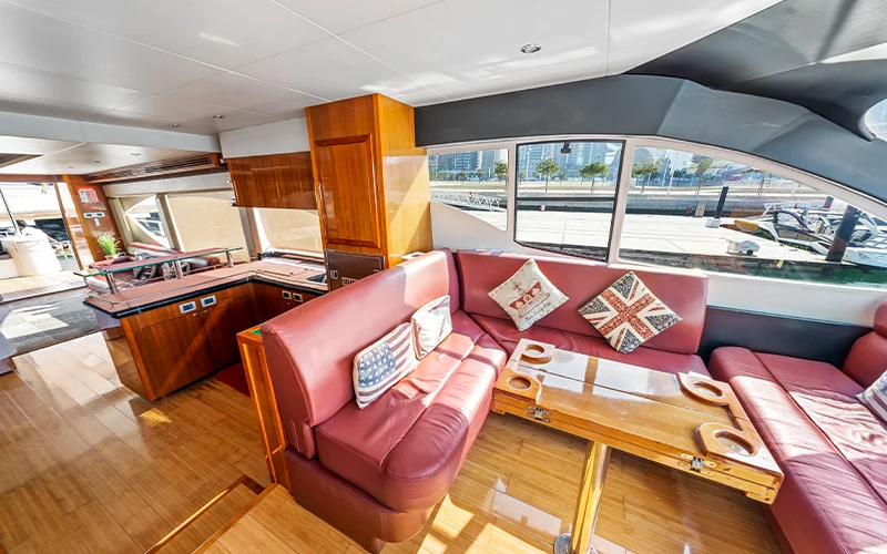 Spacious lounge inside Big Daddy Yacht featuring cream leather sofas, glass-top center table, and large side windows for natural light