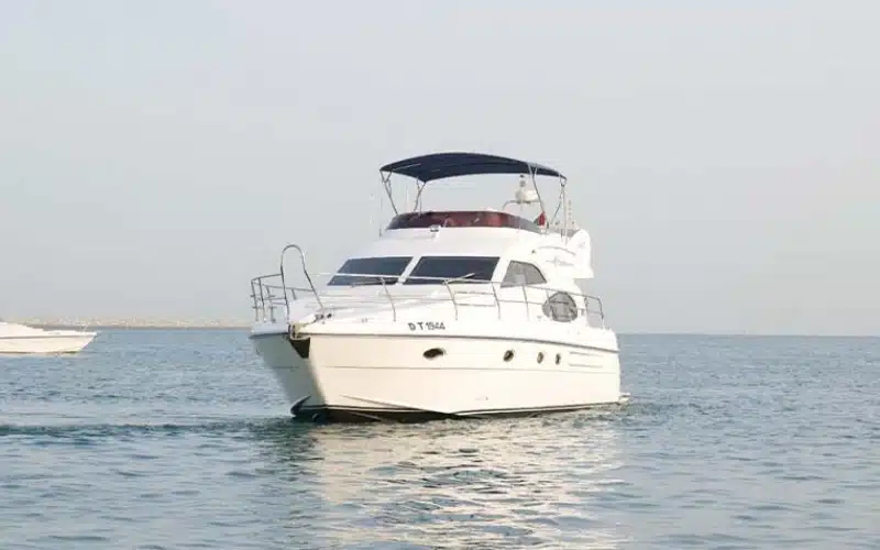 Side profile of Wrong 1 Yacht anchored near the marina, showcasing its clean white finish and open aft deck with teak flooring