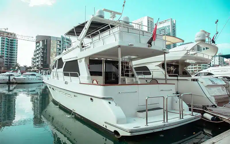 Aft deck of Gulf King Yacht featuring an outdoor dining area with cushioned chairs and teak flooring overlooking the sea