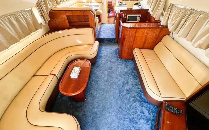 Luxurious main salon aboard Integrity yacht with cream leather sofas, wooden flooring, panoramic windows and built‑in entertainment console