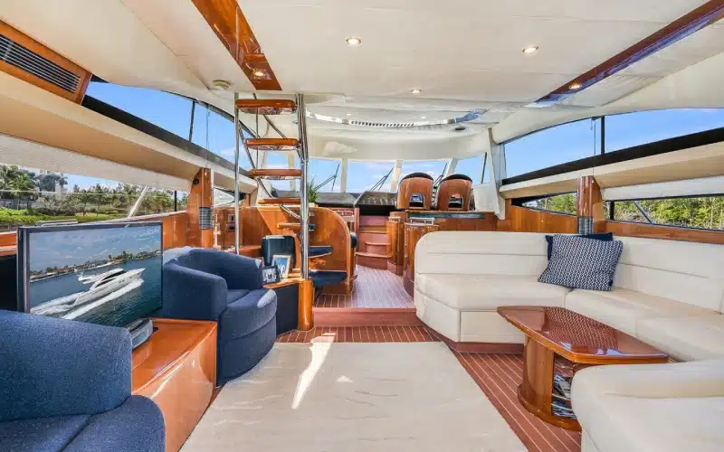 Bright salon aboard Superfly Yacht featuring L‑shaped cream seating, large panoramic windows, and polished wood trim ideal for social gatherings