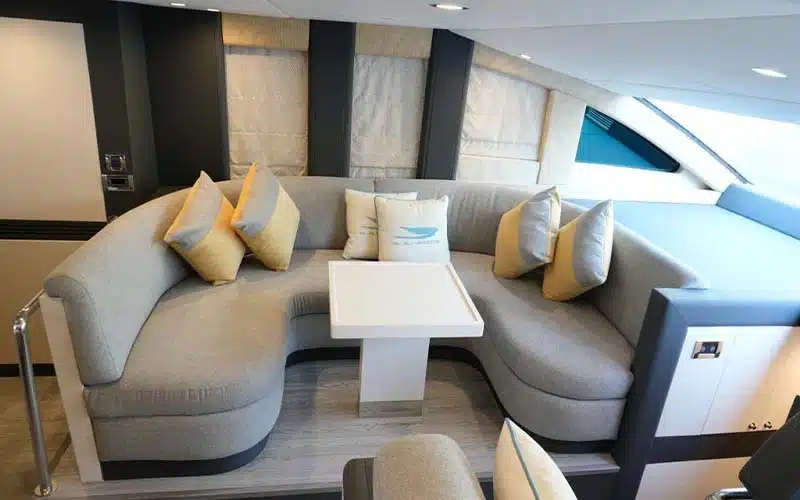 Bright salon aboard Ocean Seeker 1 yacht featuring wraparound seating, panoramic windows, and a polished wood interior with ambient lighting