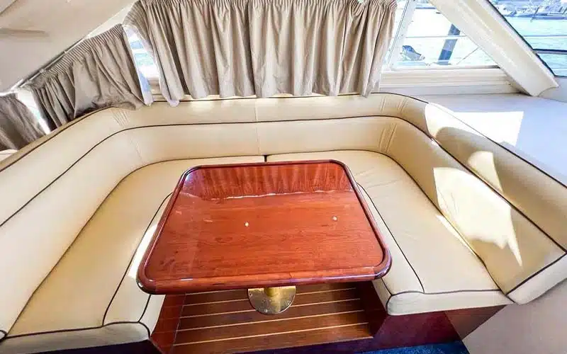 Spacious lounge aboard Integrity Yacht featuring wraparound sofas, elegant wood accents, large windows, and a serene ambiance ideal for relaxation at sea