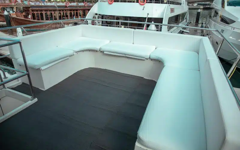 Spacious main salon of Gulf King Yacht featuring cream leather sofas, ambient ceiling lights, and panoramic windows offering ocean views