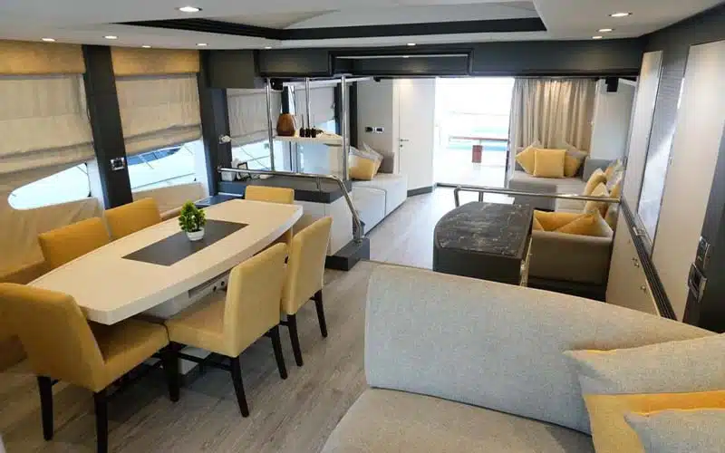 Formal dining area inside Ocean Seeker 1 yacht showcasing a wood dining table, cushioned seating, and sea views through large side windows