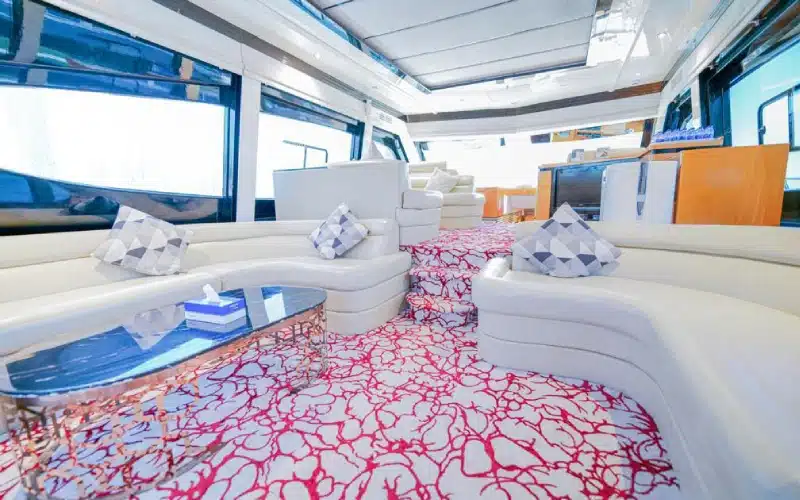 Air-conditioned main salon aboard Sea Fish Yacht featuring plush sofas, entertainment system, and panoramic side windows