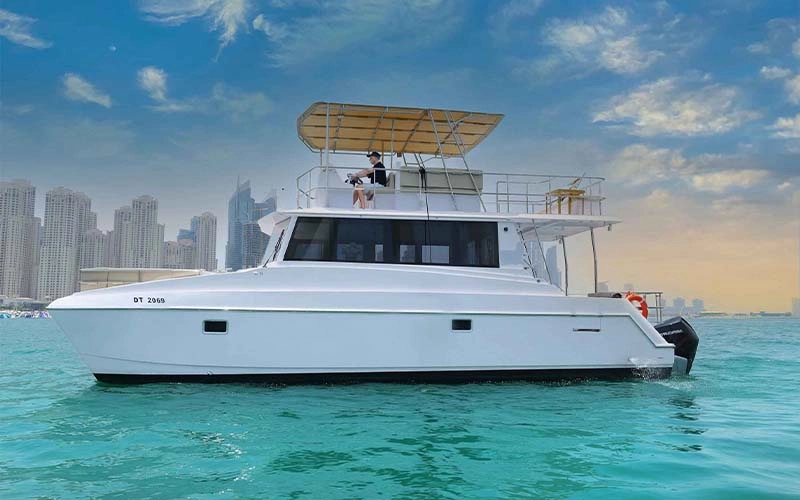 Side view of The Bird anchored near Chalkidiki coastline, showcasing flybridge and sunpads