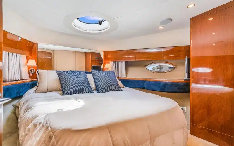 Guest bedroom aboard Superfly Yacht featuring a double bed, reading lights, wooden storage cabinets, and a porthole window for natural light