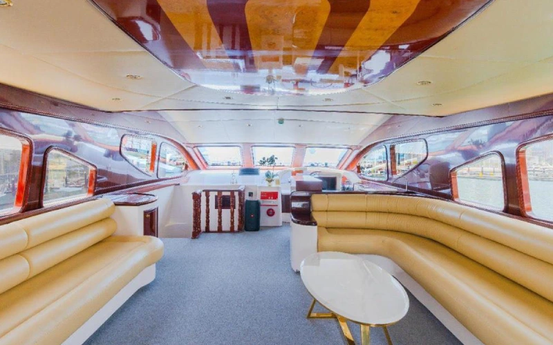 Modern dining area aboard Ocean Seeker 2 with a polished wooden table, cushioned seating, and decorative overhead lighting
