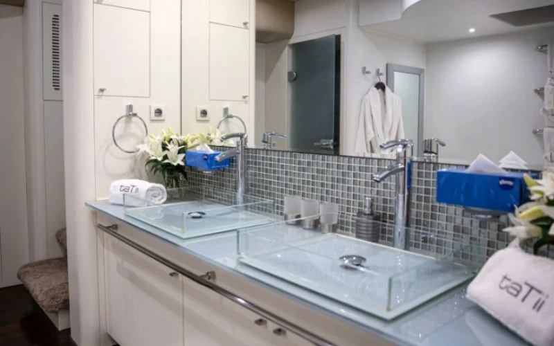 Modern bathroom with glass shower, marble counter, and chrome fixtures inside Khalili Yacht