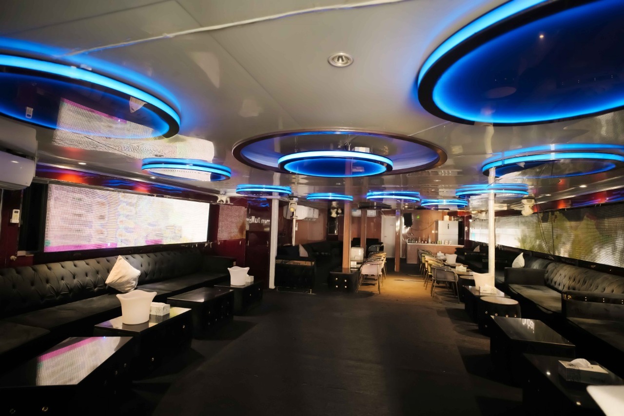 The modern and luxurious interior lounge of a Mala Yachts vessel, featuring plush black leather sofas and stylish blue LED lighting, showcasing the premium experience of a yacht rental in Dubai.