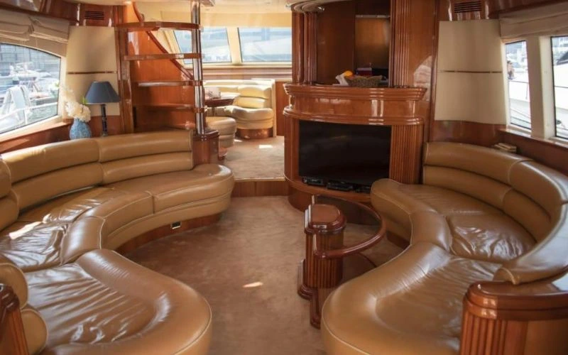 Spacious yacht salon with curved leather seating and wood paneling aboard a Mala Yachts vessel – premier yacht rental Dubai experience.