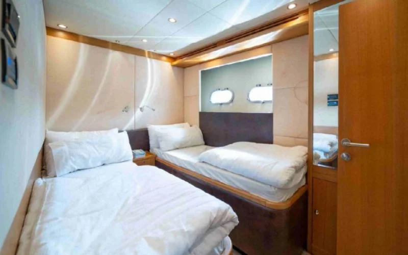 Spacious double bedroom aboard the Kronos yacht featuring twin beds and soft lighting – enjoy premium comfort with Mala Yachts’ yacht rental in Dubai.