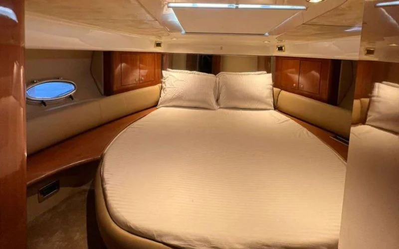 Cozy bedroom cabin aboard the Cranchi yacht with soft bedding and warm tones – relax in luxury with Mala Yachts’ exclusive yacht rental in Dubai.