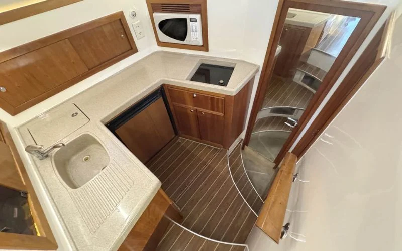Compact kitchenette inside the Riviera yacht with modern amenities – dine with comfort during your Mala Yachts yacht rental in Dubai.