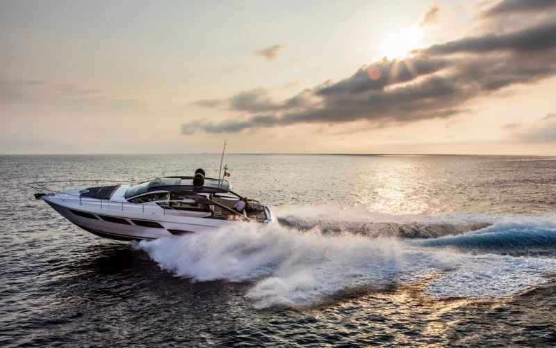 A sleek white luxury yacht from Mala Yachts speeding across the water at sunset, showcasing a premium option for yacht rental in Dubai.