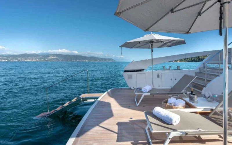 Spacious stern deck of the Tiberias yacht by Malayachts.ae, featuring sun loungers, umbrellas, a swim platform, and beautiful sea views.