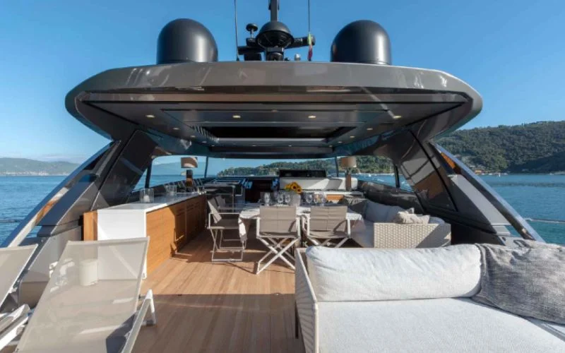 The inviting upper deck of the Tiberias yacht by Malayachts.ae, featuring an al fresco dining table, seating, and lounge areas, with a panoramic view.