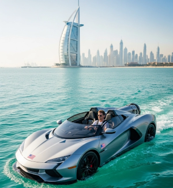 A man wearing sunglasses is driving a silver, sports-car-like watercraft on the calm ocean. In the background, the sail-shaped Burj Al Arab hotel and the modern Dubai city skyline are visible under a clear, sunny sky.